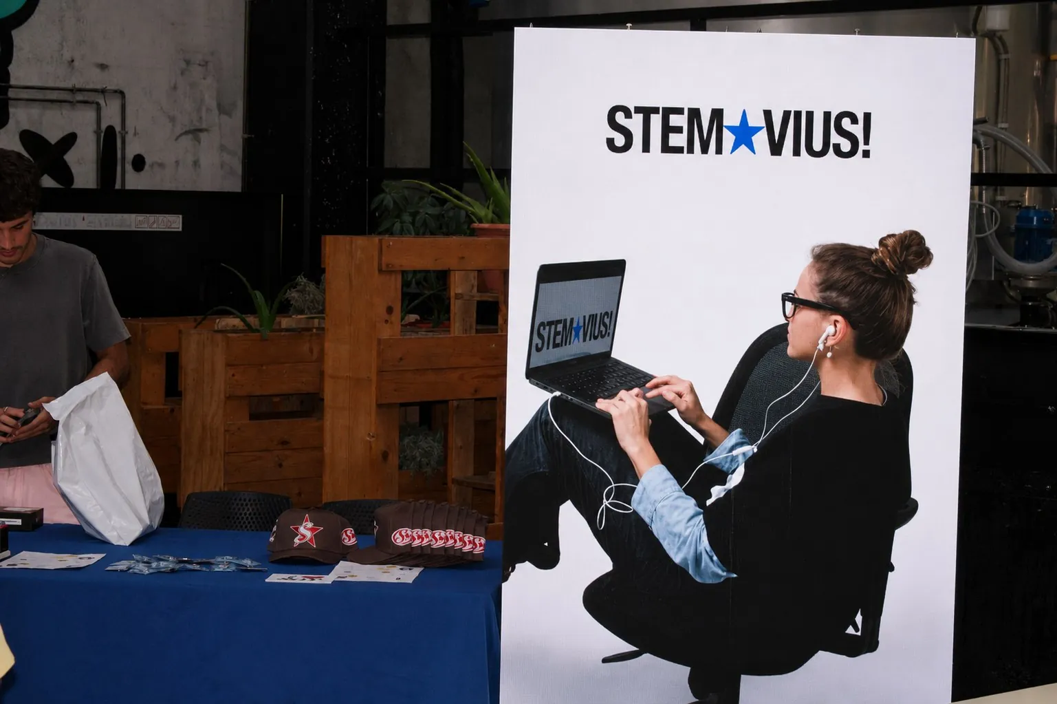 Stand STEMVIUS en el Krea Market con lona gráfica de marca, mesa azul y merchandising