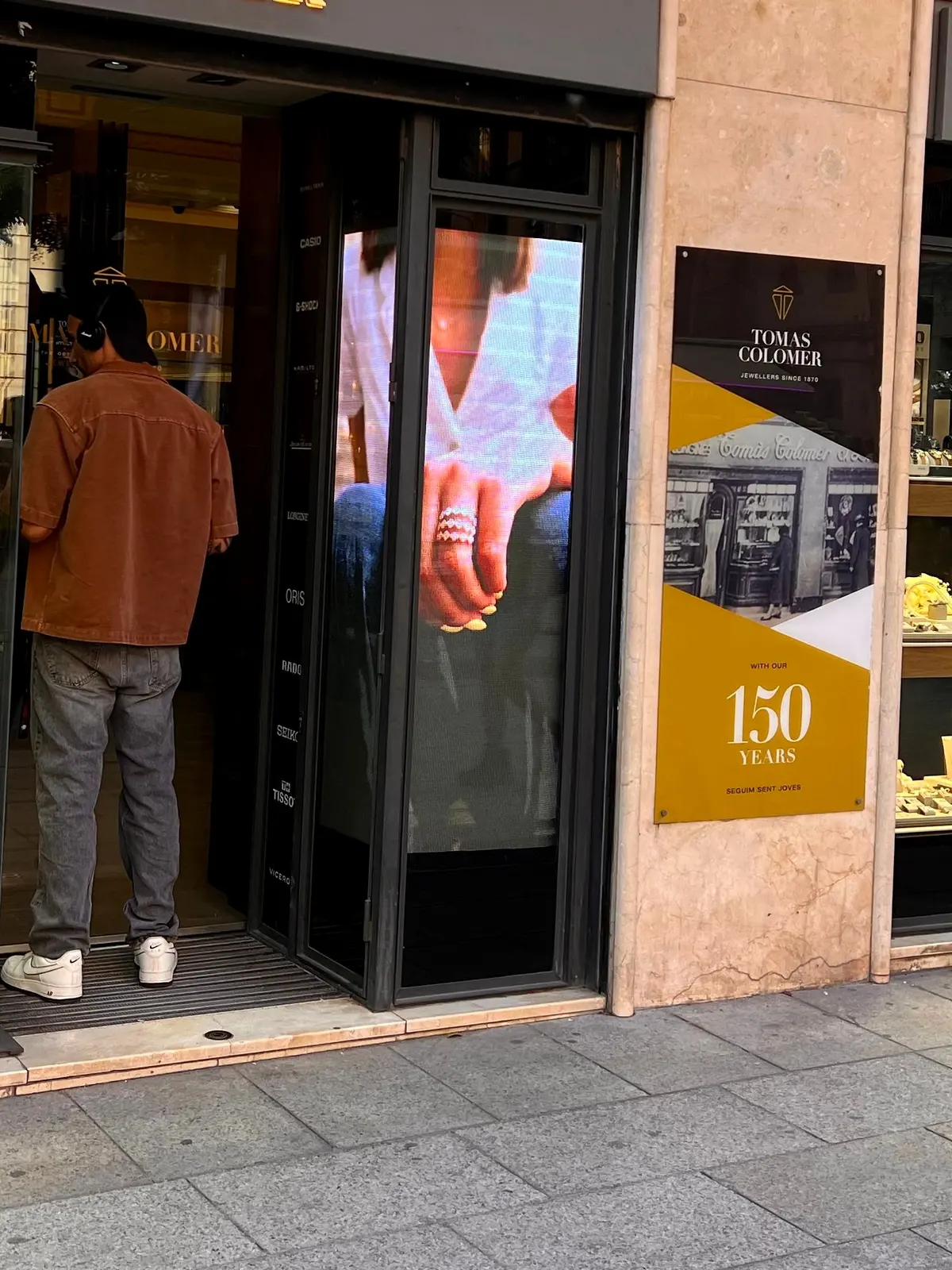 La pantalla LED ya instalada en la entrada de Tomas Colomer, encendida, junto a la placa del 150 aniversario