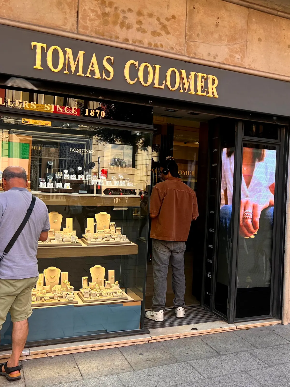 Escaparate de la joyería Tomas Colomer con la pantalla LED encendida junto a la puerta