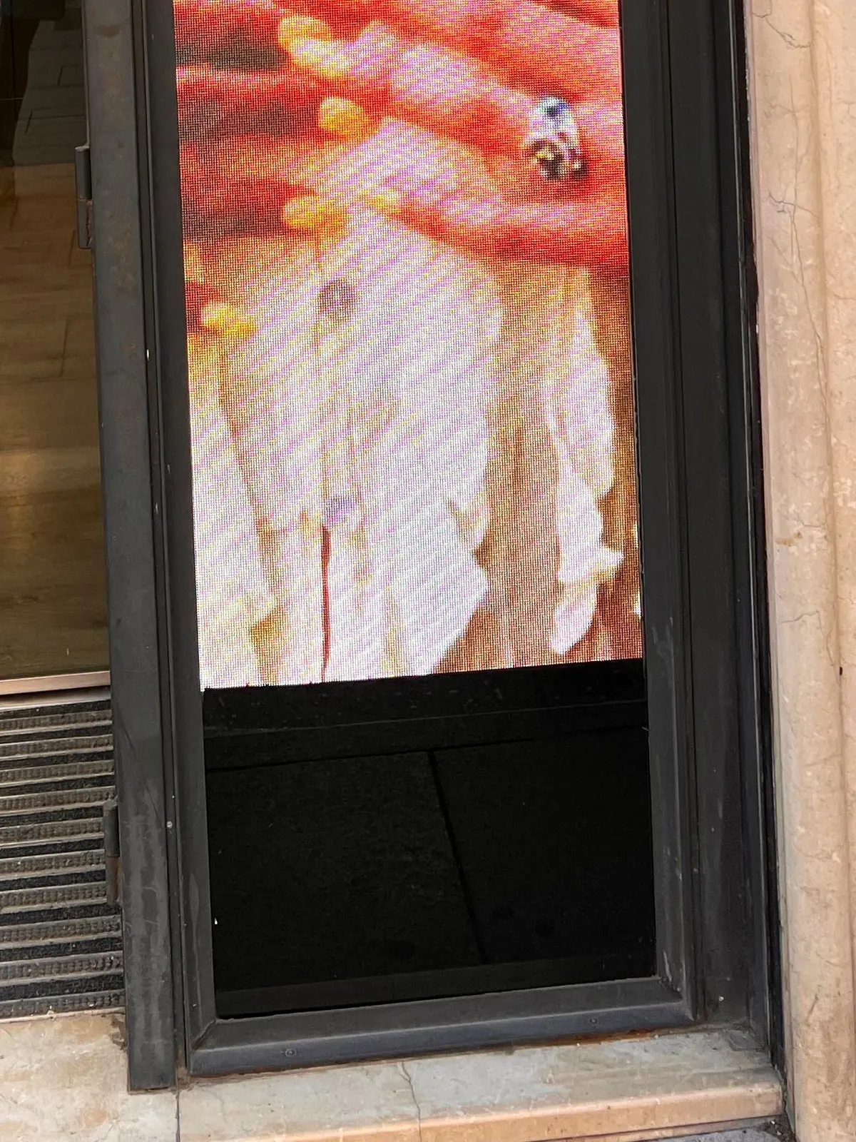 Parte baja de la pantalla LED: zócalo negro, carpintería y encuentro con el umbral de piedra