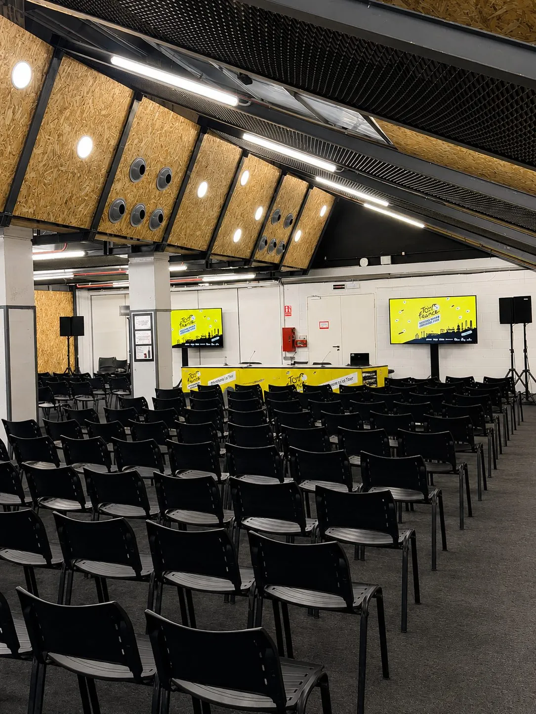 Sala de prensa del Palau Sant Jordi con mesa presidencial y pantallas de refuerzo con la gráfica del Tour de France